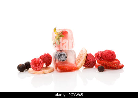 Lyophilisation fraises, framboises, groseilles, bleuets et bananes et petits fruits congelés dans des cubes de glace isolé sur fond blanc. Banque D'Images