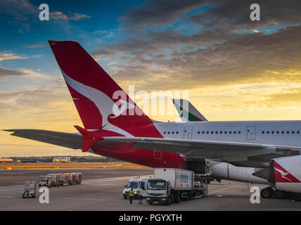 Queue d'un Airbus A380 de Qantas "super-jumbo" jet au coucher du soleil dans l'aéroport Heathrow de Londres, avec un chargement de camion de transport de l'air dans l'altitude d'attente Banque D'Images