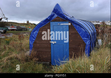 Une remise faite à partir d'un bateau retourné sur Lindisfarne, Holy Island, dans le Northumberland. L'habitacle est recouvert d'une bâche bleue et a une porte bleue Banque D'Images