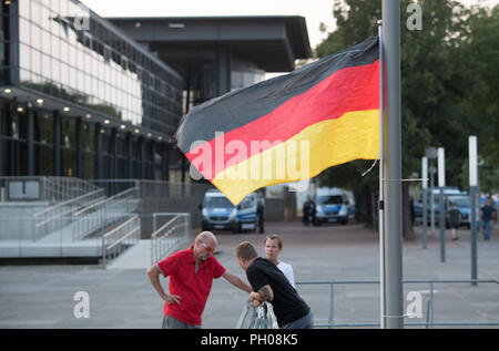 28 août 2018, l'Allemagne, Dresden : un drapeau national allemand avec des attaches de câble est relié à un pôle lanterne devant le parlement de l'état à Dresde, dans l'arrière-plan sont les véhicules de la police. Une veillée par les citoyens du cercle de l'anti-Islam mouvement Pegida initialement reçu peu de soutien à Dresde le mardi. Photo : Ralf Hirschberger/dpa Banque D'Images