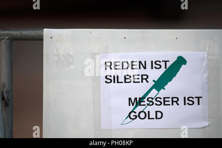 28 août 2018, l'Allemagne, Dresden : une affiche avec l'inscription 'Reden ist Silber, Messer ist Gold' est attaché à une barrière devant le parlement de l'état à Dresde. Une veillée par les citoyens du cercle de l'anti-Islam mouvement Pegida initialement reçu peu de soutien à Dresde le mardi. Photo : Ralf Hirschberger/dpa Banque D'Images