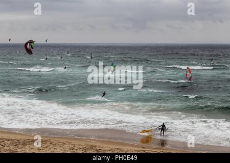 Les surfeurs à la plage de Guincho sous ciel nuageux au printemps au Portugal Banque D'Images