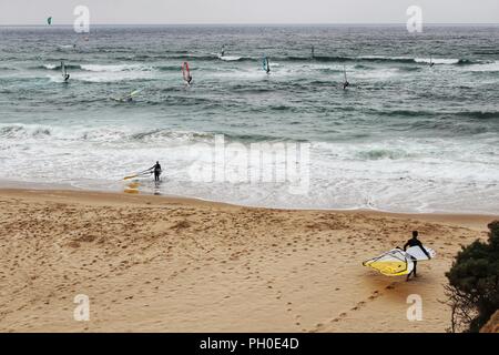 Les surfeurs à la plage de Guincho sous ciel nuageux au printemps au Portugal Banque D'Images