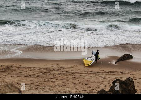 Les surfeurs à la plage de Guincho sous ciel nuageux au printemps au Portugal Banque D'Images