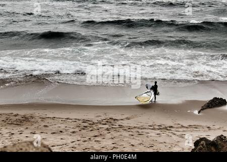 Les surfeurs à la plage de Guincho sous ciel nuageux au printemps au Portugal Banque D'Images