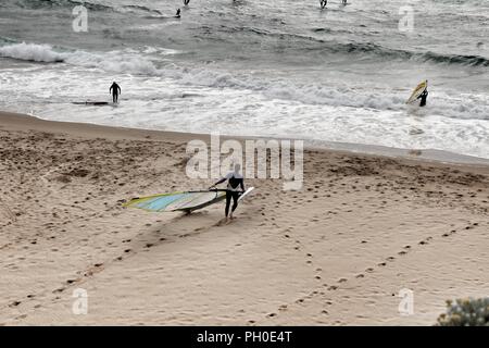 Les surfeurs à la plage de Guincho sous ciel nuageux au printemps au Portugal Banque D'Images