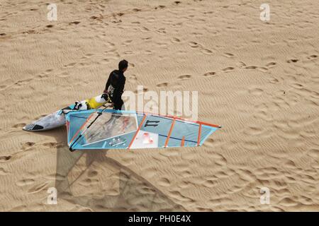 Les surfeurs à la plage de Guincho sous ciel nuageux au printemps au Portugal Banque D'Images