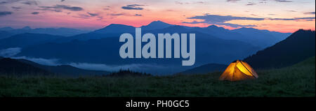 Orange brillant tente dans les montagnes spectaculaires sous ciel du soir Banque D'Images