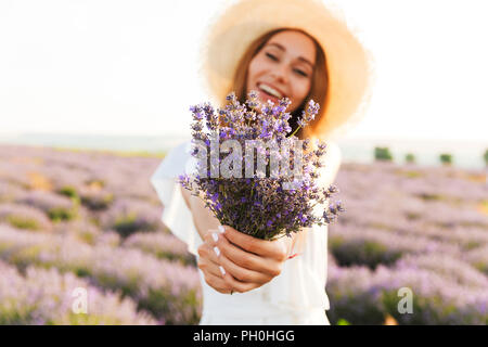 Happy young girl in straw hat holding Bouquet de lavande au domaine Banque D'Images