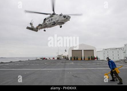 Japon (17 juin 2018) l'Aviation maître de Manœuvre (l'aéronef) 3e classe Miranda Browning, affectés à la commande de transport maritime militaire navire-hôpital USNS Mercy (T-AH 19) pour le Partenariat du Pacifique 2018 (PP18), détient la cale et les chaînes comme un SH-60K Sea Hawk, jointe à la Force maritime d'autodéfense japonaise (JMSDF), décolle à la merci d'envol au cours d'une équipe de formation médicale bilatérale entre forage et miséricorde. personnel JMSDF USNS Mercy fait escale à Yokosuka et Tokyo pour promouvoir les relations entre les marins de la Marine américaine et les citoyens japonais par l'entremise d'activités culturelles exchan Banque D'Images