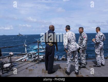 De Thaïlande (18 juin 2018) - Le Capitaine Lex Walker (à gauche), des visites de la Marine royale thaïlandaise distingués visiteurs à travers la plate-forme arrière de missiles USS Mustin (DDG 89) au cours de la préparation et de la formation Coopération à flot (CARAT) Thaïlande 2018. L'exercice multilatéral (carat), dans son 2e tour et impliquant les États-Unis, Singapour et la Thaïlande, est conçu pour renforcer les capacités mutuelles dans un large spectre de la guerre navale qui permettent aux marines partenaire d'opérer efficacement ensemble comme une force maritime unifié. Banque D'Images