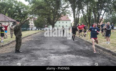 23e Brigade d'artillerie, soldat des forces terrestres polonaises franchit la ligne d'arrivée en premier lors de la course de relais 4x400 qui a eu lieu à la célébration de la 243e anniversaire de l'Armée de terre polonaise qui s'est tenue à la base des Forces canadiennes à Boleslawiec, Pologne, le 14 juin 2018. Des soldats américains affectés à la 91e bataillon du génie, 1re Brigade de blindés de combat, l'équipe de 1re Division de cavalerie, et la Compagnie B, 151e Bataillon des transmissions du Corps expéditionnaire, Caroline du Sud, la Garde nationale s'est classé deuxième et troisième. Banque D'Images