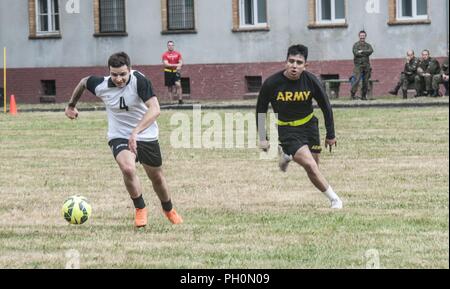 23e Brigade d'artillerie, soldat des forces terrestres polonaises s'exécute après un ballon de football lors d'un match contre des soldats américains affectés à la 91e bataillon du génie, 1re Brigade de blindés de combat, l'équipe de 1ère Division de cavalerie et la Compagnie B, 151e Bataillon des transmissions du Corps expéditionnaire, Caroline du Sud, de la Garde nationale au cours d'un match de football commémorant le 243e anniversaire de l'Armée de terre polonaise qui s'est tenue à la base des Forces canadiennes à Boleslawiec, Pologne, le 14 juin 2018. La célébration conjointe inclus une base-wide, exécuter les événements sur le terrain, et un gâteau symbolique. Banque D'Images