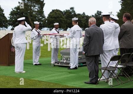 Normandie, France (19 juin 2018) l'hôpital de la Marine américaine sur la garde d'honneur de Naples tient le drapeau américain sur le reste de l'opérateur radio 2e classe Julius "Henry" Pieper "pre" est joué au cours d'un service funèbre au cimetière américain de Normandie. Henry Pieper et son frère jumeau, opérateur radio 2e classe Ludwig "Louie" Pieper, ont tous deux été tués lorsque leur navire, Landing Ship Tank (LST) 523, a frappé une mine sous-marine au large de la côte de la France le 19 juin 1944. Louie's reste a été trouvé immédiatement, mais demeure de Henry n'ont pas été identifiés jusqu'à décembre 2017. La famille a demandé que Henry être enterré en Normandie n Banque D'Images