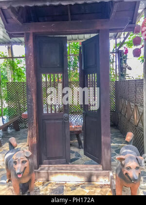 Vintage jardin public décoré avec des chiens statue en face de l'ancienne porte d'entrée en bois. Banque D'Images