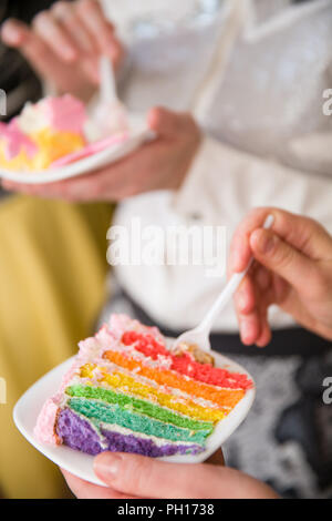 Les gens manger de délicieux gâteau arc-en-ciel. Des gâteaux colorés pour une fête d'anniversaire. Mains avec du gâteau. Close-up of hands holding cuillères sur le point de s Banque D'Images