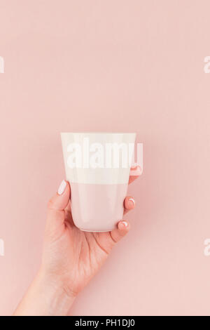 Creative Image de femme hand holding Coffee cup with copy space sur fond rose millénaire dans un style minimaliste. Modèle de concept pour le féminin, blog Banque D'Images