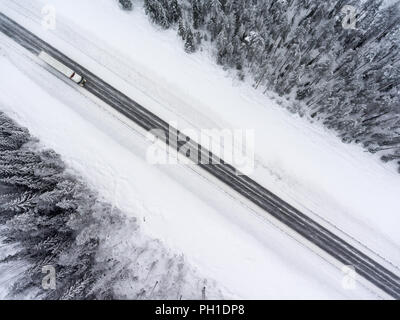 Conduite de camion semi-remorque sur blizzard hiver route asphaltée. Vue de dessus du pilotage de drone Banque D'Images