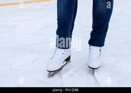 Les jambes de patinage sur glace en cuir blanc avec des patins sur la patinoire, close-up view Banque D'Images
