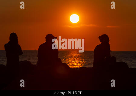 Les gens s'assoient sur la jetée et regarder le coucher de soleil sur le vignoble son à Menemsha Plage à Chilmark, Massachusetts sur Martha's Vineyard. Banque D'Images