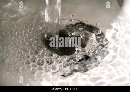 Les éclaboussures d'eau dans l'évier, Close up. Lieux aux projections d'eau verser de l'eau forte avec beaucoup de bulles d'eau dans l'évier, Close up. Banque D'Images