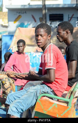 SAINT LOUIS, SÉNÉGAL - Apr 24, 2017 : Des Sénégalais dans chemise rouge monte un panier à Saint Louis, l'une des grandes villes au Sénégal Banque D'Images