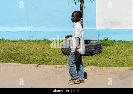 SAINT LOUIS, SÉNÉGAL - Apr 24, 2017 : petit garçon sénégalais non identifiés en chemise blanche et jeans promenades en face du pneu de voiture à Saint Louis, l'un des Banque D'Images
