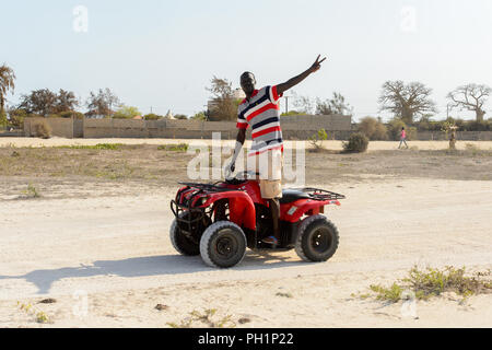 LAC ROSE, AU SÉNÉGAL - Apr 26, 2017 : Un homme monte un quad sur la côte du lac salé Lac Retba, Site du patrimoine mondial de l'UNESCO Banque D'Images