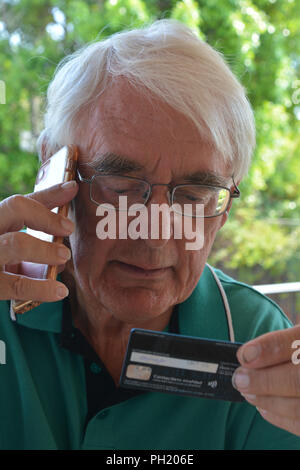 Man donnant son numéro de carte de crédit au téléphone, achats en ligne ou l'hameçonnage Banque D'Images