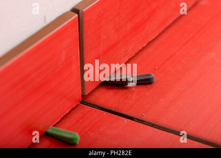 Vue rapprochée de bas d'écartement utilisée en carrelage d'un mur pour s'assurer un même écart pour le coulis entre les carreaux dans un concept de rénovation et de bricolage. Banque D'Images