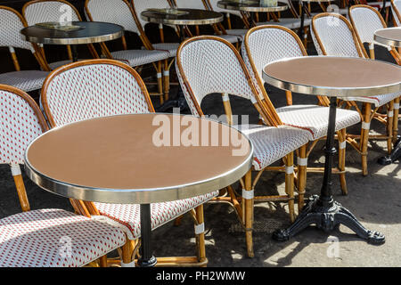Une terrasse typique à l'extérieur d'une brasserie parisienne, mis en place avec des chaises en rotin et des petites tables rondes avec une jambe de fer de fonte. Banque D'Images