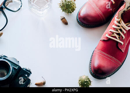 Chaussures en cuir de mode pour l'automne, printemps. bottes rouge sur un fond blanc couche avec l'appareil photo, des verres et de glands. Banque D'Images