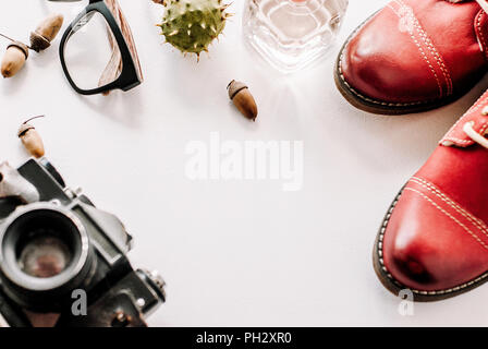 Chaussures en cuir de mode pour l'automne, printemps. bottes rouge sur un fond blanc couche avec l'appareil photo, des verres et de glands. Banque D'Images