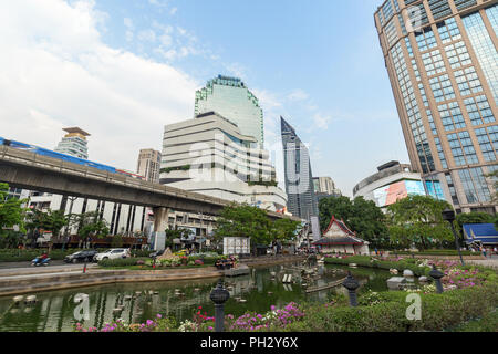 Vue sur un étang au parc Benchasiri, bâtiments modernes et d'une station du skytrain dans le centre-ville de Bangkok, Thaïlande. Banque D'Images