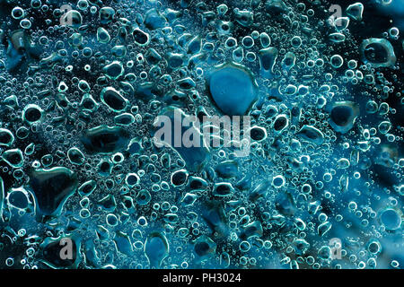 Fond noir et bleu sous le verre avec de l'eau gouttelettes d'huile et mélanger. Macro Photographie Banque D'Images
