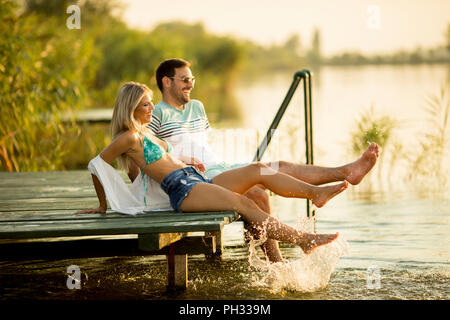 Couple assis sur la jetée en bois sur le lac de Banque D'Images