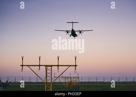 L'atterrissage de l'avion au crépuscule. L'approche de l'aéroport d'avions à turbopropulseurs. Banque D'Images