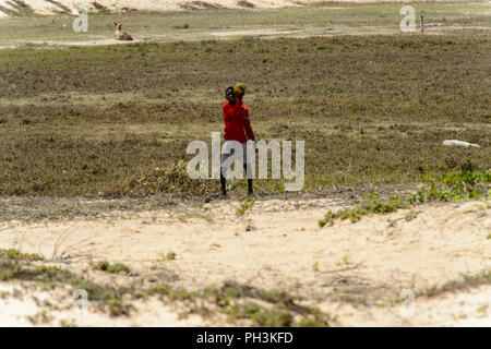 KAYAR, SÉNÉGAL - AVR 27, 2017 : garçon sénégalais non identifiés en chemise rouge se distingue avec une balle dans un beau village près de Kayar, au Sénégal Banque D'Images