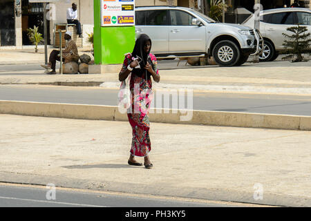 DAKAR, SÉNÉGAL - Apr 27, 2017 : femme sénégalaise non identifiés en foulard noir promenades le long de la rue à Dakar, capitale du Sénégal Banque D'Images