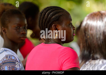OUSSOUYE, SÉNÉGAL - Apr 30, 2017 : femme sénégalaise non identifiés avec tresses en chemise rose ressemble à quelque chose dans la forêt sacrée près de Kaguit village Banque D'Images