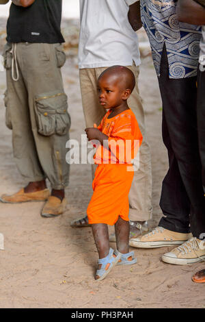 OUSSOUYE, SÉNÉGAL - Apr 30, 2017 : petit garçon sénégalais non identifiés en costume orange se trouve dans la forêt sacrée près de Kaguit village Banque D'Images