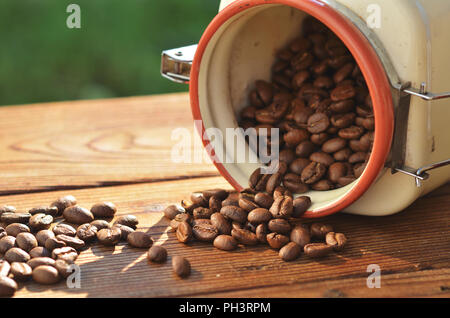 Les grains de café sont frits versé d'un beau pot d'argile sur une planche en bois Banque D'Images