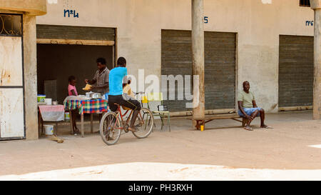 Route de BISSAU, GUINÉE B. - 1 mai 2017 : local non identifié, l'homme est assis sur le vélo dans un village en Guinée Bissau. Encore beaucoup de gens dans le pays l Banque D'Images