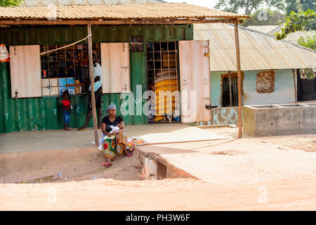 Route de BISSAU, GUINÉE B. - 1 mai 2017 : femme locale non identifiés est titulaire d'un bébé par dans un village en Guinée Bissau. Encore beaucoup de gens dans le pays vivre Banque D'Images