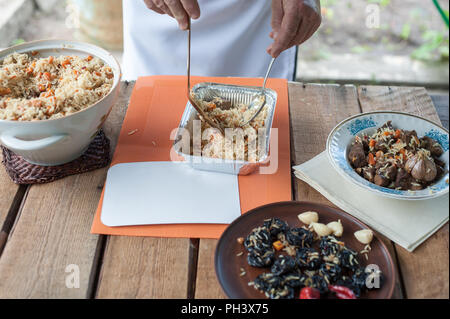 Chef de mettre le riz, le boeuf et les légumes dans un plat à usage unique livraison Banque D'Images