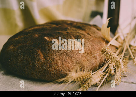 Au levain bio miche de pain avec le jaune d'or et des grains de blé germés crampons sur table cloth, atmosphère rurale Banque D'Images