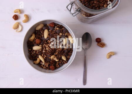 Granola au chocolat maison avec noix dans un bol, déposer à plat blanc Banque D'Images