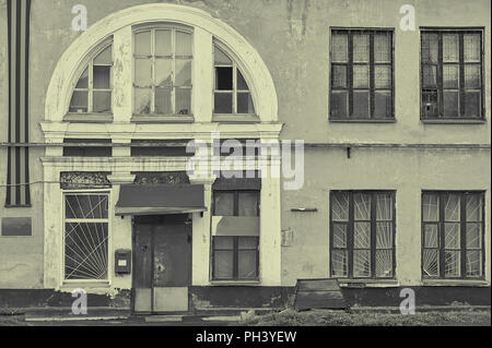 Ancienne usine abandonnée façade avec de grandes fenêtres et une porte en métal rouillé en noir et blanc Banque D'Images
