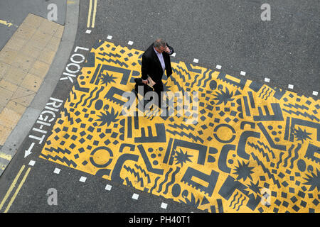 Art géométrique Kishimoto et businessman walking with briefcase sur jaune passage piétons près de Aldersgate, dans la ville de London, UK KATHY DEWITT Banque D'Images