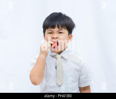 Portrait of cute Asian boy eating strawberry rouge sur fond blanc, Banque D'Images